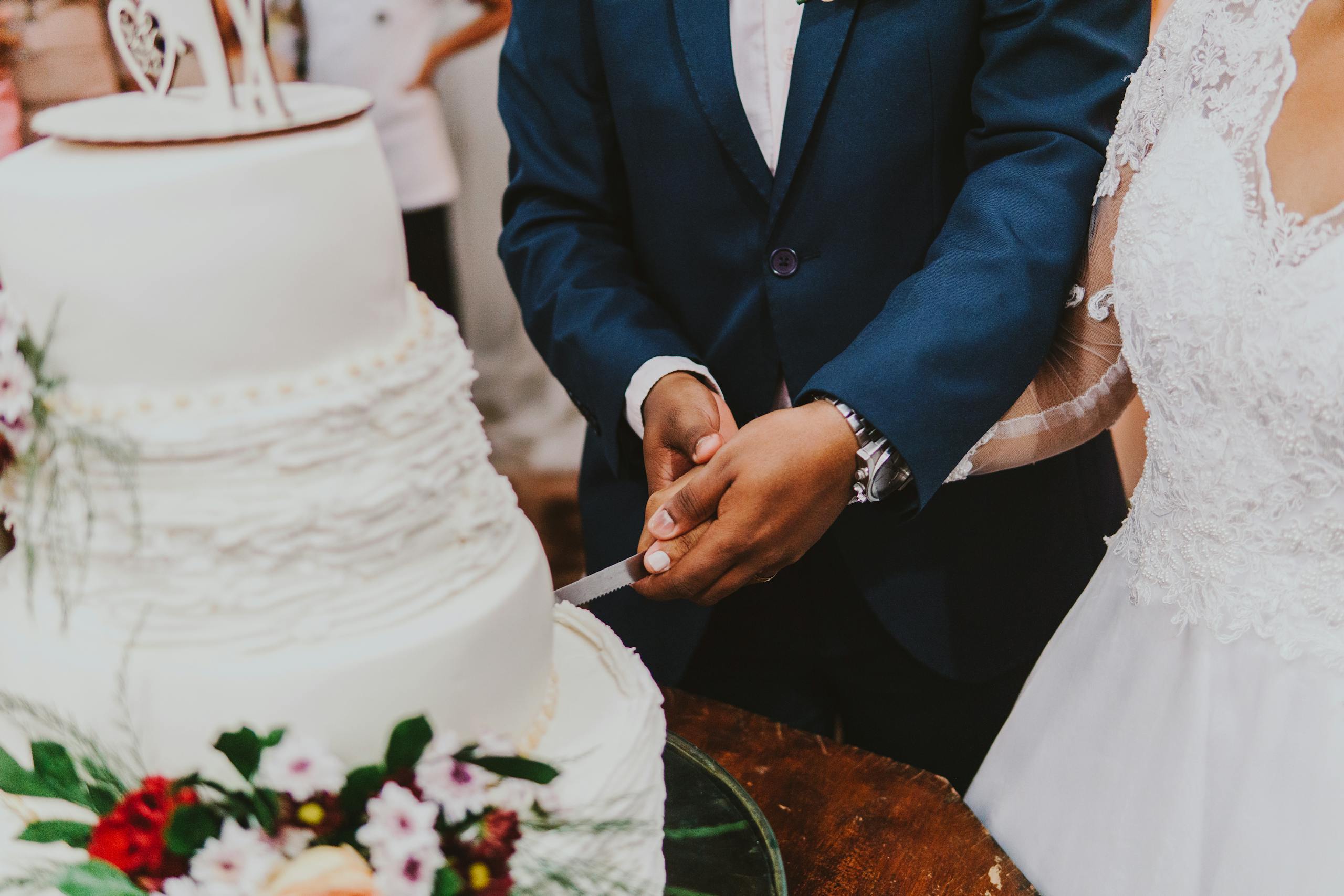 Close-up of a bride and groom cutting their wedding cake with floral decorations.