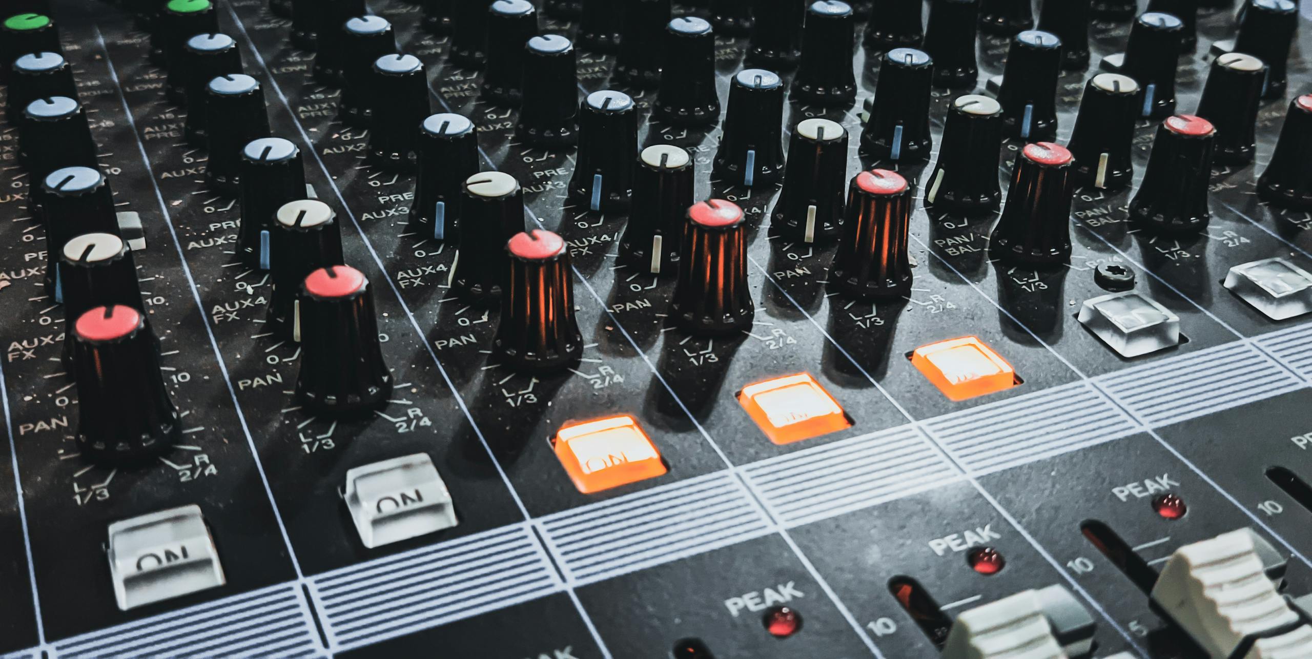 Detailed shot of an audio mixer highlighting knobs and glowing lights, perfect for sound engineering insights.